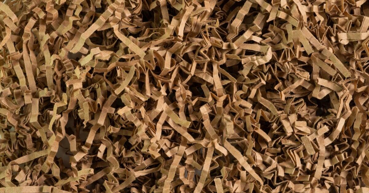 An extreme close-up of dark brown, crumpled shredded paper filler in a package and filling the frame.