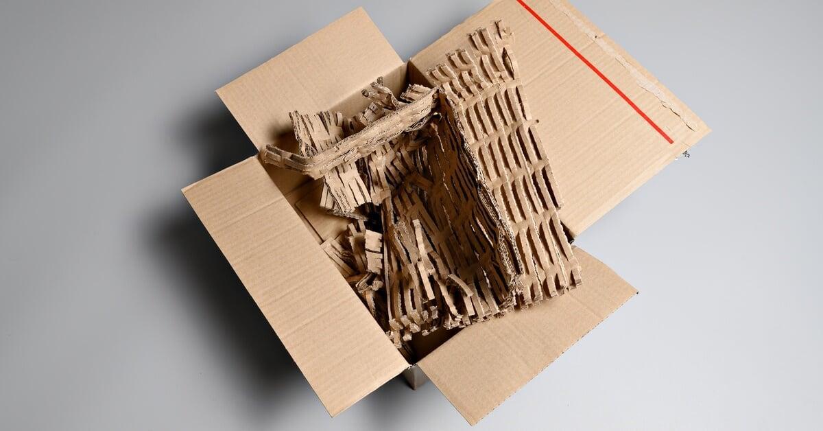 An open cardboard box filled with densely packed corrugated strips and bubble wrap for protective cushioning.