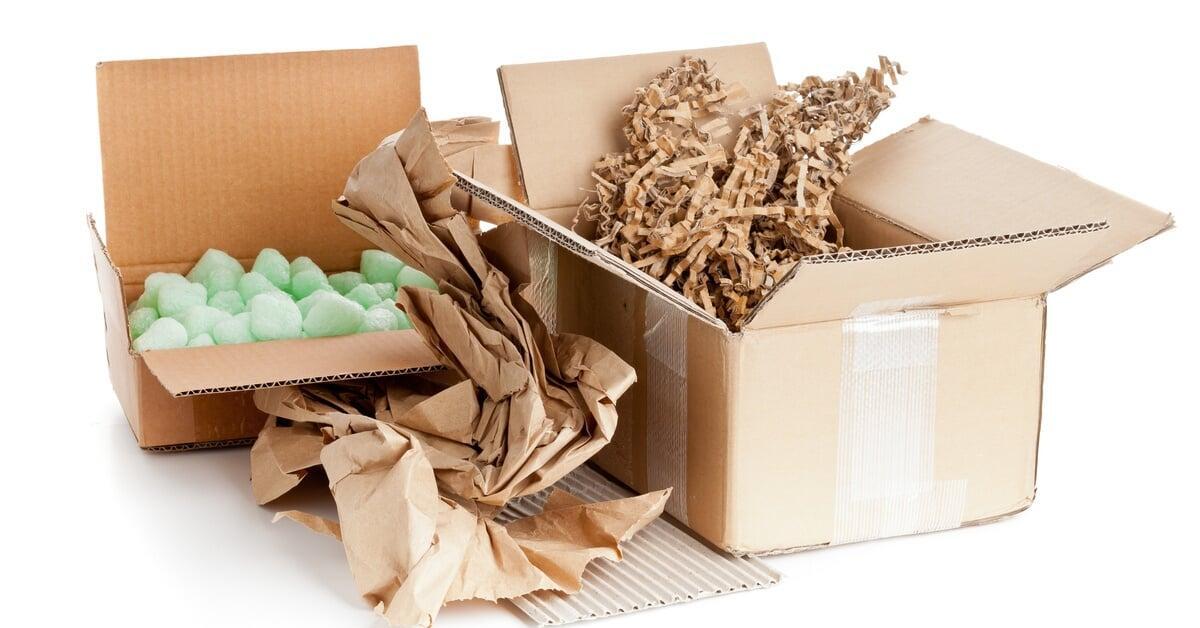 A variety of recyclable packaging materials, including cardboard, paper sheets, and tubes, arranged on a flat surface.