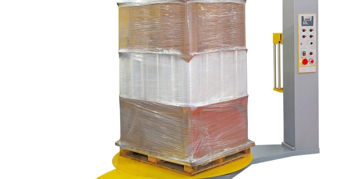 A layer of transparent stretch film encloses boxes on a pallet as the pallet sits on the machine’s platform.