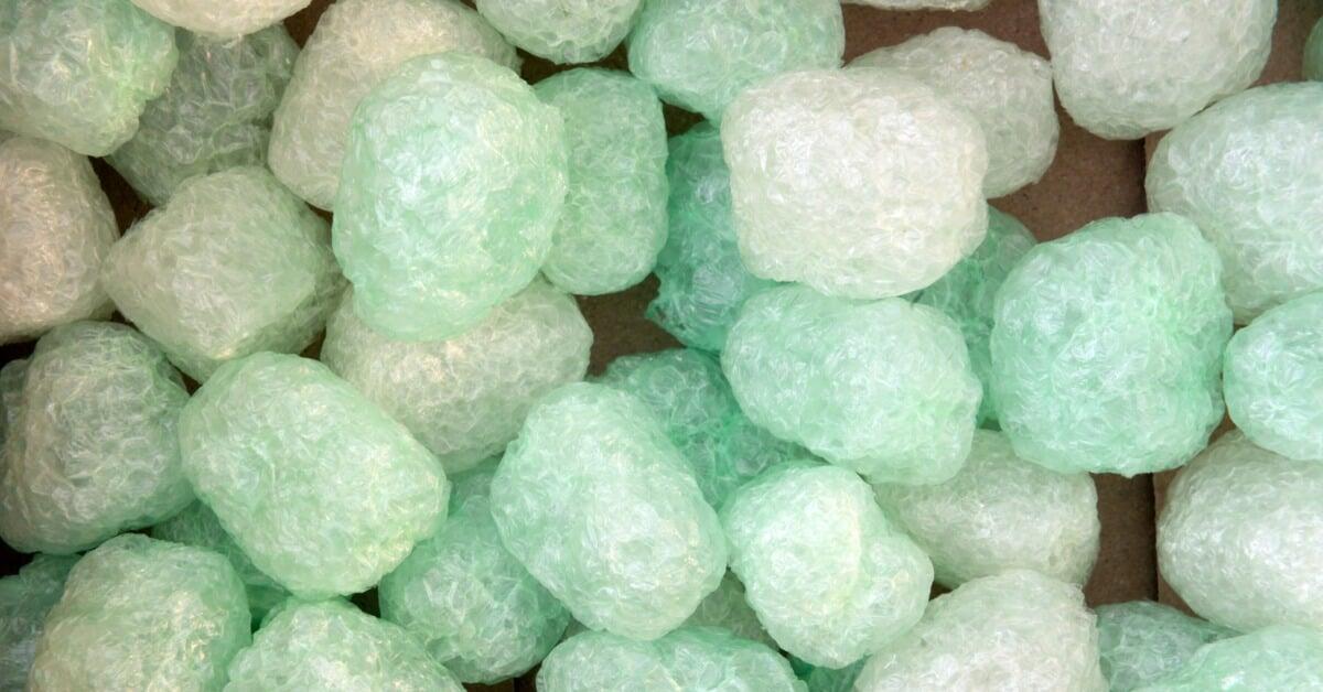 Green packing peanuts fill the frame in a close view, showing rounded shapes, light texture, and varying tones of green.