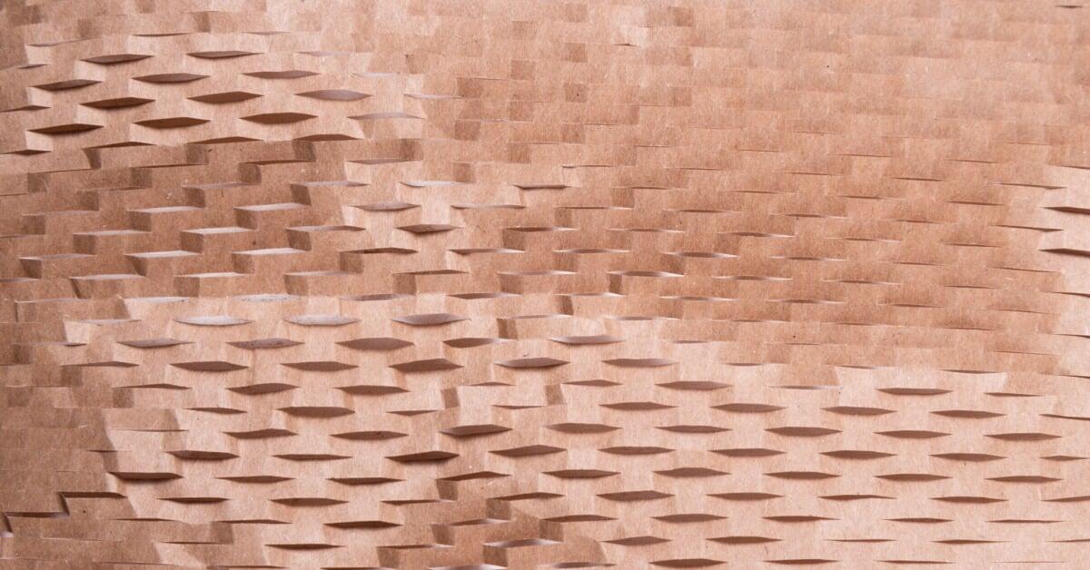 Brown paper packaging filler spreads across the surface, showing a layered pattern with cut, raised, and textured sections.
