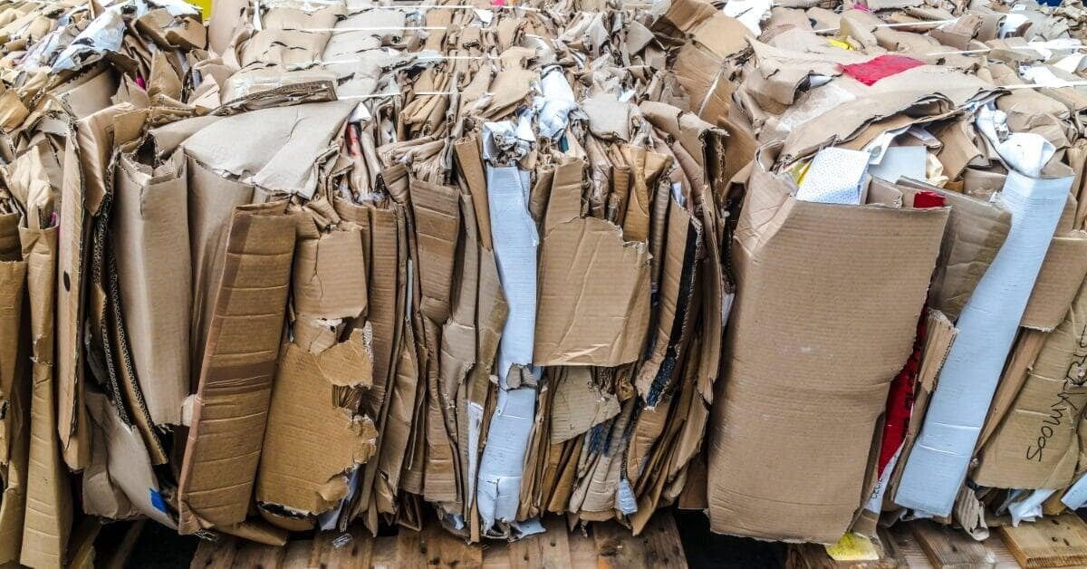 A close-up view of flattened cardboard pieces packed together in large bales resting on wooden pallets.