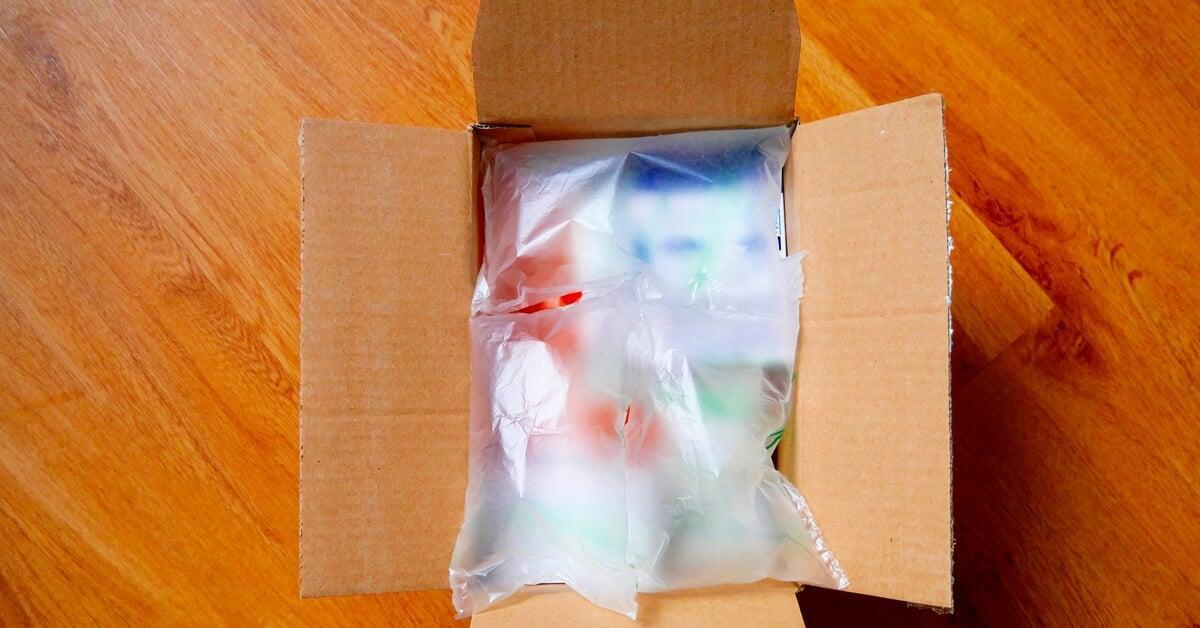 An overhead view of an open cardboard box with several air pillows placed on top of the items for protection.