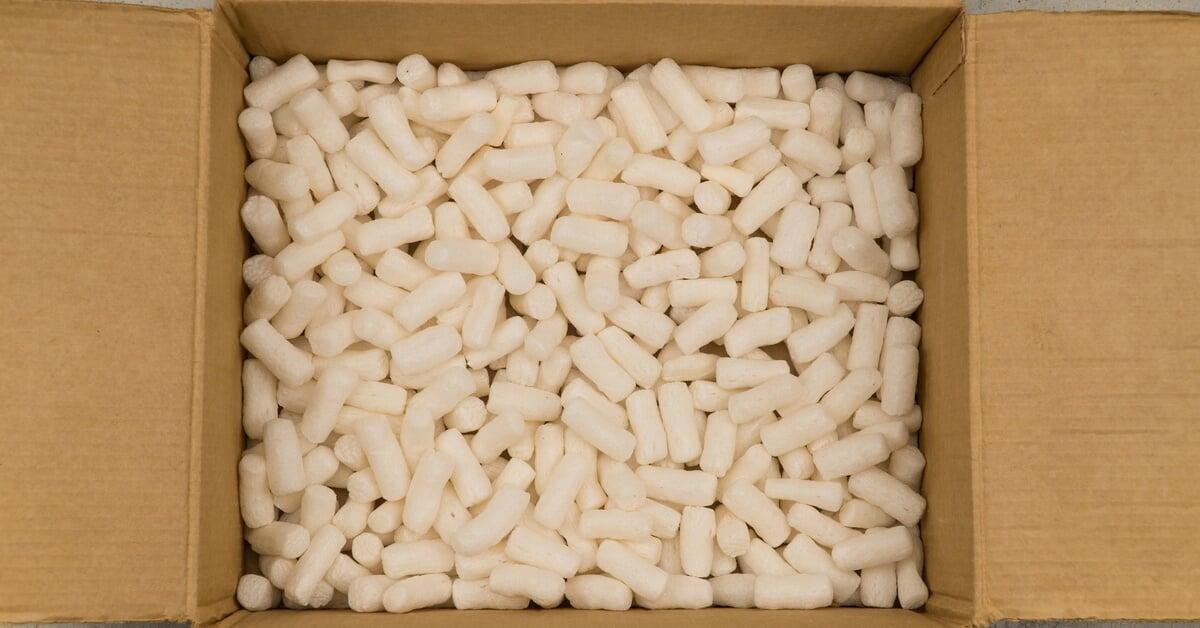 An overhead view of an open cardboard box filled with white Styrofoam packing peanuts for safe packaging.