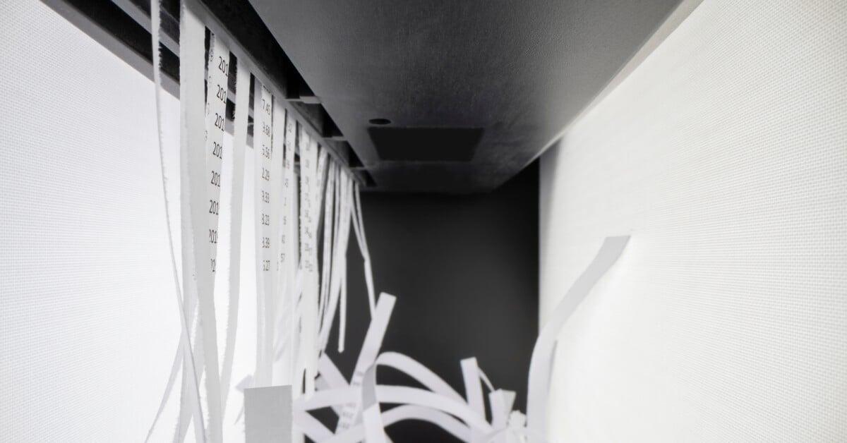 A close-up ofA close-up of a paper shredder cutting documents into thin strips, with shredded paper visible below the shredder. a paper shredder cutting documents into thin strips, with shredded paper visible below the shredder.