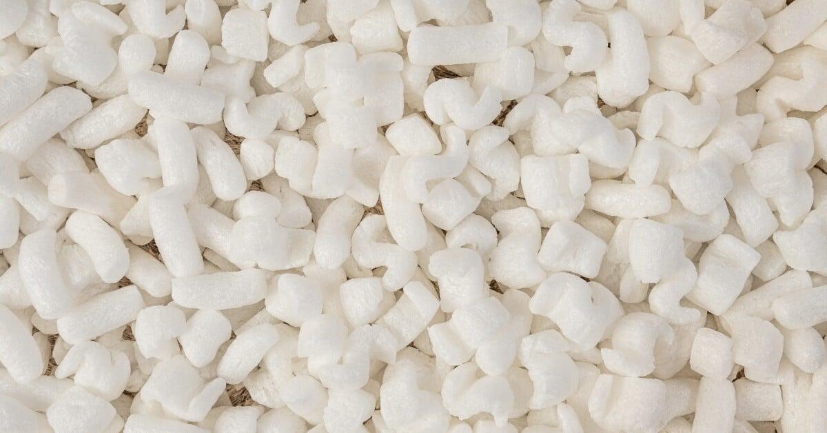 A high-angle view of a partly worker's hands placing packed products into cardboard boxes for shipping.