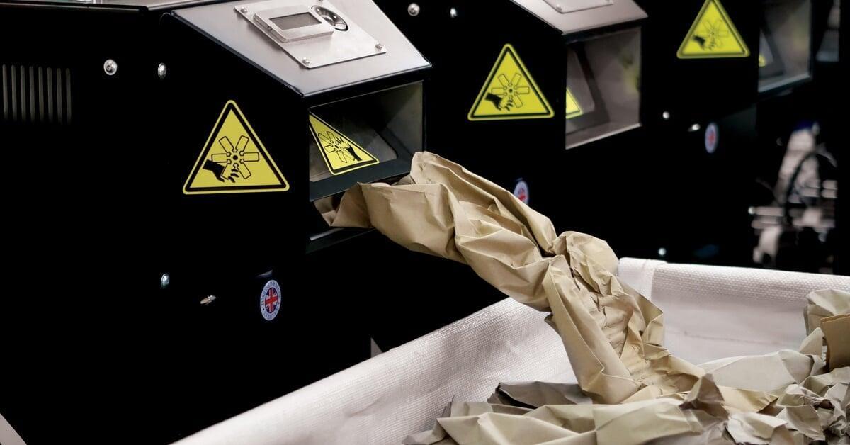 An industrial kraft paper void fill machine produces crumpled paper for packaging and sends it into a large bin.