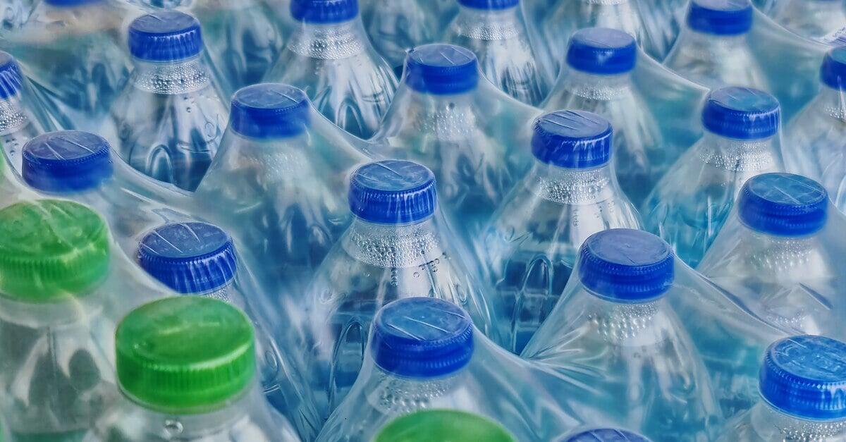 Clear stretch wrap tightly covering plastic bottles filled with clear liquid. Some bottles have blue caps and some have green.