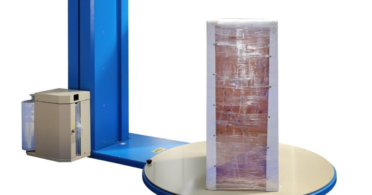 A tall load is wrapped tightly with stretch wrap. The load is on a blue stretch wrap machine's turntable.